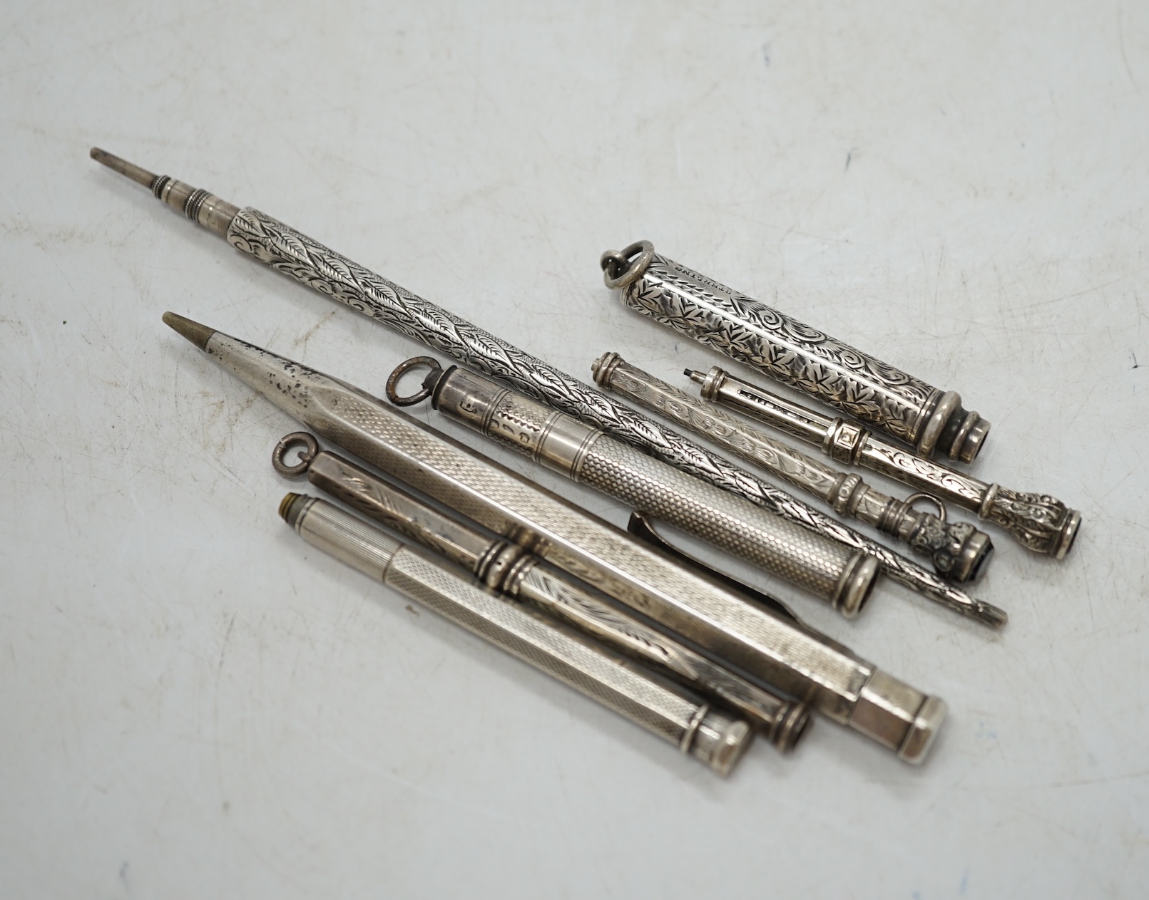 An engine turned silver cased Yard-O-Led pencil, three silver cased propelling pencils, a sterling cased propelling pencil and three white metal cased pencils. Condition - fair